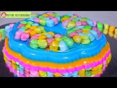 there is a colorful cake with candy on the top and bottom layer that looks like it has been frosted