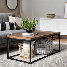 a living room with a gray couch and wooden coffee table in the middle, surrounded by white rugs