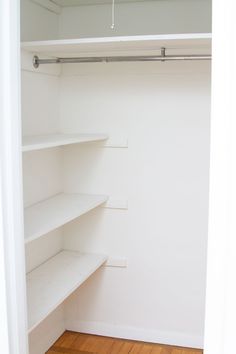 an empty closet with white shelves and wood floors