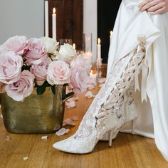 a bride's wedding dress and high heeled shoes with flowers on the floor