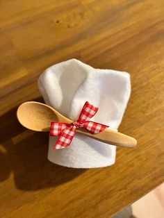 a wooden spoon sitting on top of a white cloth napkin with a red checkered bow