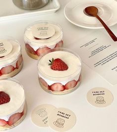 four small desserts with strawberries in them on a table