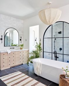 a white bath tub sitting in a bathroom next to a sink and mirror on the wall