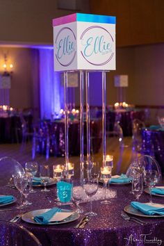 the table is set for an event with purple linens and blue napkins on it