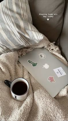 an open laptop computer sitting on top of a bed next to a cup of coffee