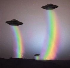 three flying saucers in the sky with a rainbow colored light coming from one side