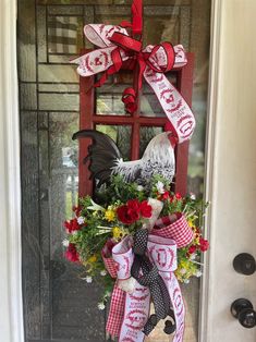 a rooster door hanger decorated with flowers and ribbon, sitting on the front door