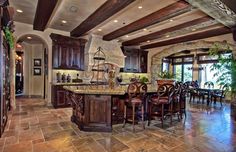 a large kitchen with wooden cabinets and marble counter tops, along with an island in the middle