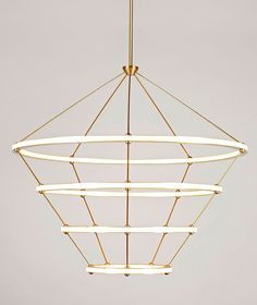 a modern chandelier hanging from the ceiling with circular lights in gold and white