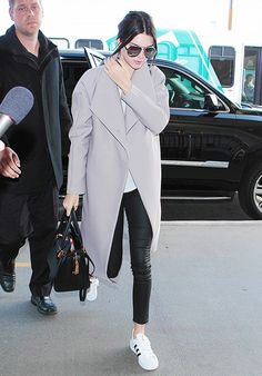 the woman is walking through an airport with her hand on her face and wearing sunglasses