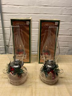 two glass vases sitting on top of a table next to each other with christmas decorations in them