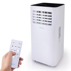 a person holding a remote control next to a small air conditioner