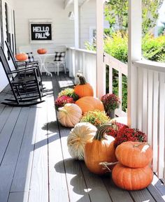 pumpkins and gourds are sitting on the porch