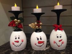 three white vases with faces painted on them, one has a candle in it