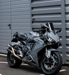 a silver motorcycle parked in front of a garage door next to a parking space with metal doors