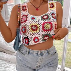 a woman taking a selfie while wearing a crochet top and denim shorts