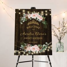 a welcome sign with flowers and greenery is displayed in front of a string of lights