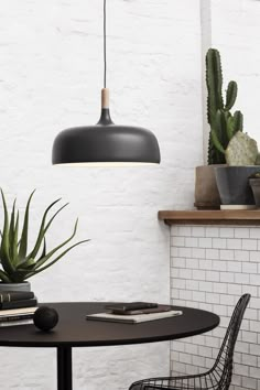 a black table with some books and plants on it next to a white brick wall