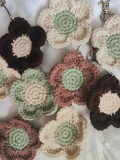 several crocheted flower keychains are laying on a white surface with two keys in the middle