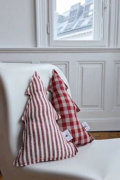 two red and white pillows sitting on top of a white chair