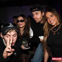 a group of people standing next to each other at a party with one person making the peace sign