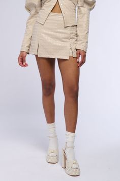 In a league of your own. The AKIRA Label Better Off Alone PU Houndstooth Skort In Ivory is part of a two-piece ensemble featuring a sleek faux leather composition, textured felt houndstooth patterning, a high rise waist, back pouch pockets, and an attached skirt overlay on the front with dual hem slits. Complete with a mini short silhouette from the back, rounded hems, a pull-on fit, and a tonal back zip closure. Amp up your look by styling with the coordinating AKIRA Label Better Off Alone PU Houndstooth Button Down Blouse In Ivory.  - Fabric: 50% Polyurethane 46% Polyester 2% Spandex, Lining: 100% Polyester - Some Stretch - Imported  (all measurements are approximate from size small) - 13” Waist to Hem  - Model is 5’8” Product ID: 395638  (all measurements are approximate from size 1X) - Better Off Alone, Ivory Fabric, Mini Short, Pocket Pouch, High Rise, Two Piece, Faux Leather, Sleek, Leather