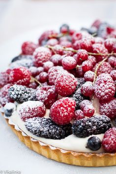 a tart topped with fresh berries and powdered sugar on top of each other