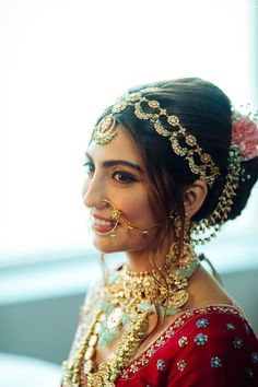 a woman in a red dress with gold jewelry on her neck and headpieces