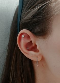 a close up of a person's ear wearing a pair of silver hoop earrings