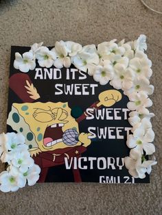 a spongebob sign with white flowers on the floor next to it that says and its sweet sweet sweet victory