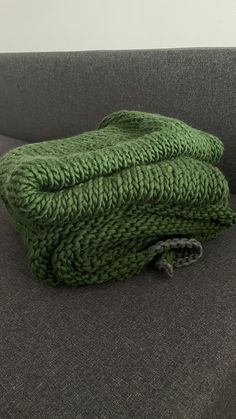 two green towels sitting on top of a gray couch