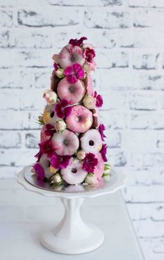 a white cake topped with donuts and pink flowers