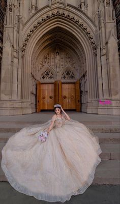 a woman in a wedding dress is sitting on the steps outside an old building with large doors