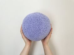 a person is holding a purple ball in their hands against a white wall with text overlay