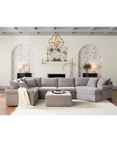 a living room with a large sectional couch and footstool in front of a fireplace