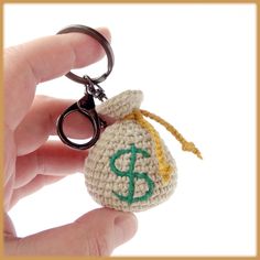 a crocheted keychain with a bag on it is being held by someone's hand