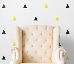 a white chair sitting in front of a wall with black and yellow triangles on it