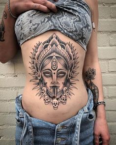 a woman's stomach with an intricate tattoo design on her belly and the head of a