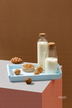 milk and cookies are sitting on a blue tray next to a glass bottle with some milk in it