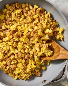 scrambled eggs and ham in a pan with wooden spoons on the stove top, ready to be cooked