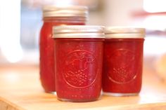 three jars filled with red liquid sitting on top of a table