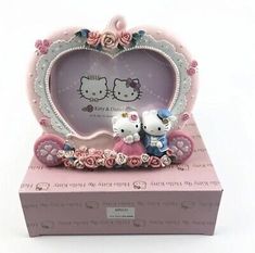 two hello kitty figurines sitting on top of a pink box