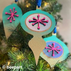 three ornaments hanging from a christmas tree with blue, pink and green decorations on them