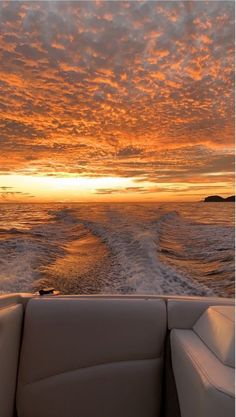 the sun is setting over the ocean as seen from a motor boat in the water