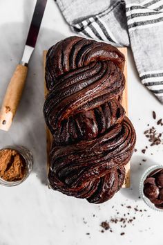 a loaf of chocolate bread sitting on top of a wooden cutting board next to some spices