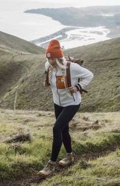 a woman with a backpack is walking up a hill