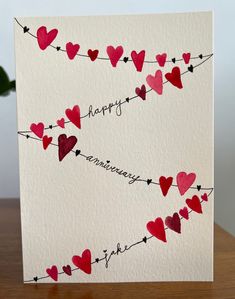 a valentine's day card with hearts hanging from a line