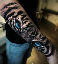 a man's arm with a tiger tattoo on it and blue eyes in the center