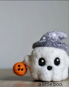 there is a small stuffed animal that has a pumpkin in it's mouth and wearing a knitted hat