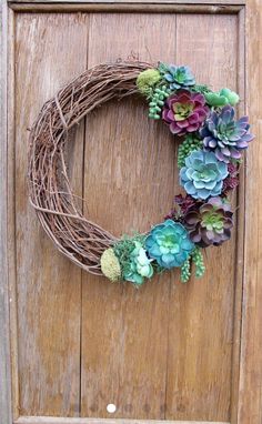 a wreath with succulents is hanging on a door